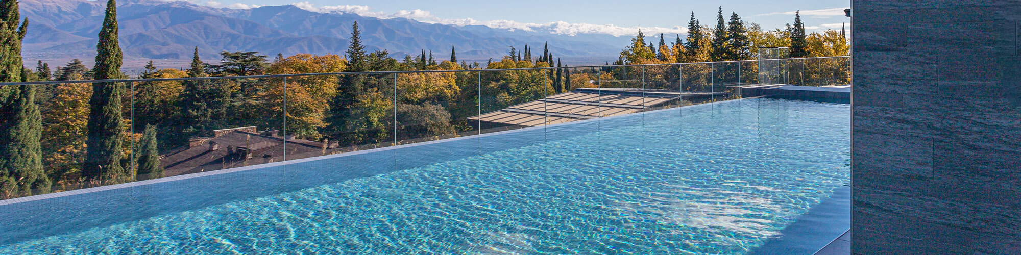A Pool Of Water Against The Backdrop Of Mountains And A Forest W